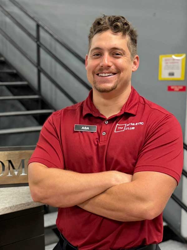 man with arms crossed in red polo inside a fitness gym in Marble Falls, TX